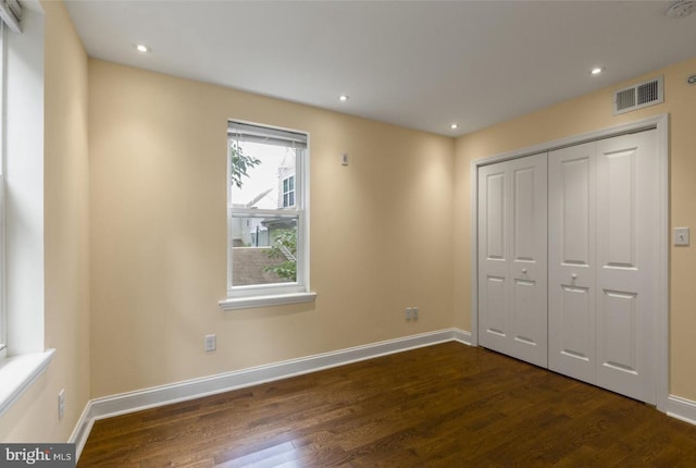 unfurnished bedroom with dark hardwood / wood-style flooring and a closet