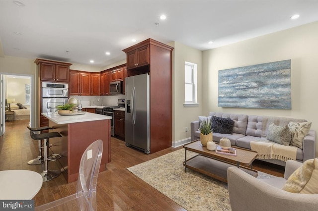 kitchen featuring dark wood-type flooring, a breakfast bar, sink, appliances with stainless steel finishes, and a kitchen island