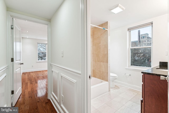 full bathroom featuring vanity, a healthy amount of sunlight, tiled shower / bath combo, and toilet