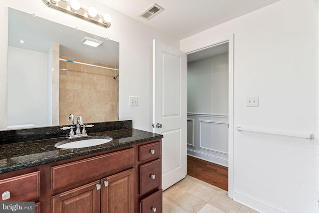 bathroom with tile patterned flooring, vanity, a tile shower, and toilet