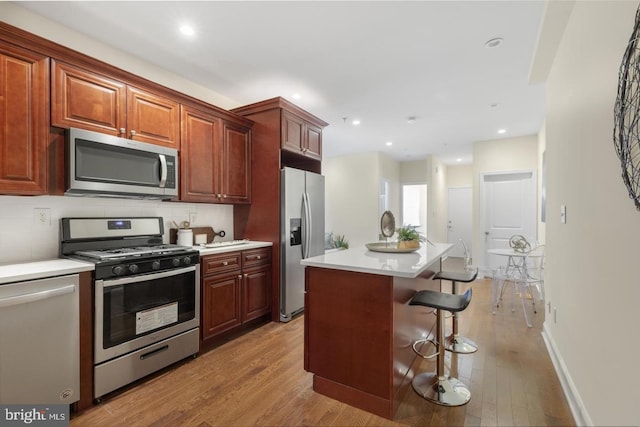 kitchen with a breakfast bar, tasteful backsplash, light wood-type flooring, a kitchen island, and stainless steel appliances