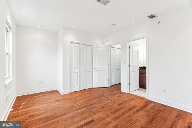 unfurnished bedroom featuring connected bathroom and light wood-type flooring