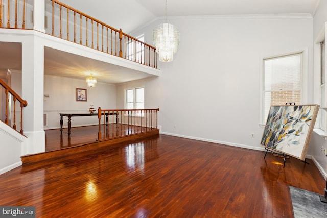 interior space featuring an inviting chandelier, hardwood / wood-style flooring, vaulted ceiling, and ornamental molding