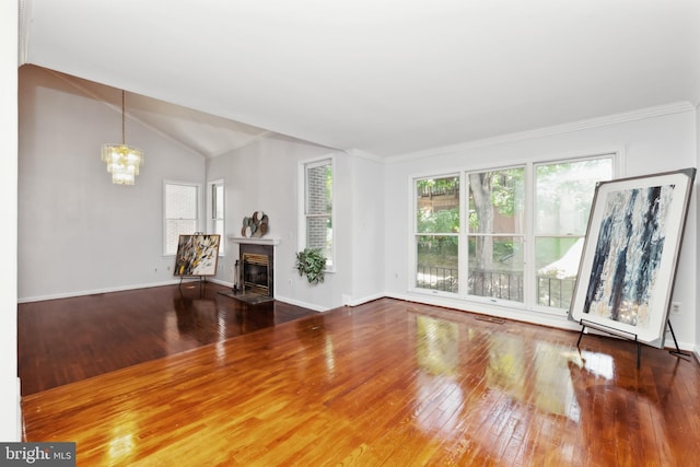 unfurnished living room featuring hardwood / wood-style flooring, crown molding, a chandelier, and vaulted ceiling