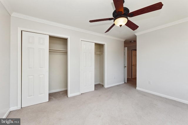 unfurnished bedroom with multiple closets, ornamental molding, light colored carpet, and ceiling fan