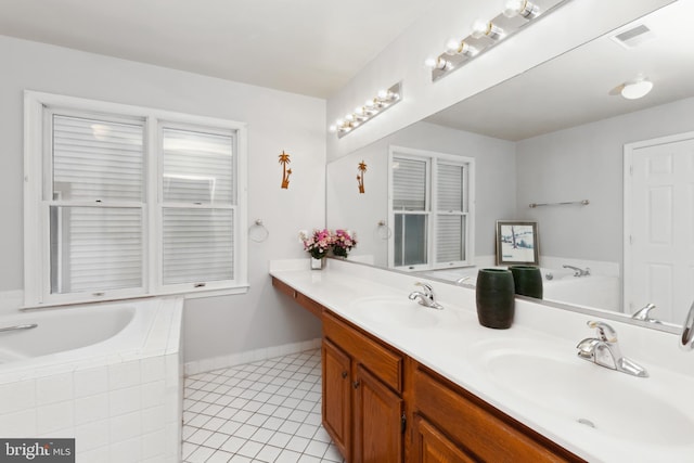 bathroom with a relaxing tiled tub, vanity, and tile patterned flooring