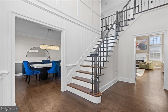 stairway with hardwood / wood-style floors, crown molding, and a high ceiling