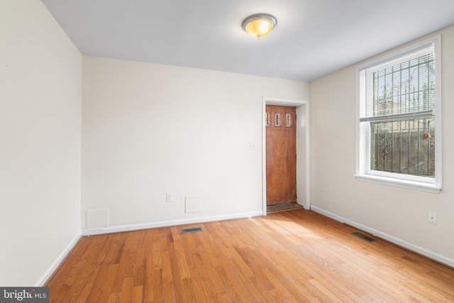 spare room featuring baseboards, visible vents, and hardwood / wood-style floors