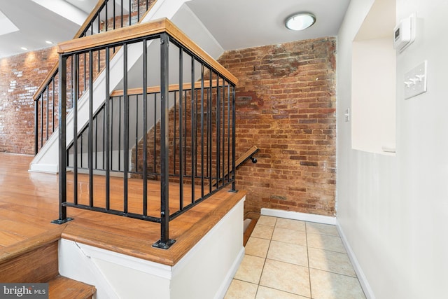 stairway featuring brick wall, baseboards, and tile patterned flooring