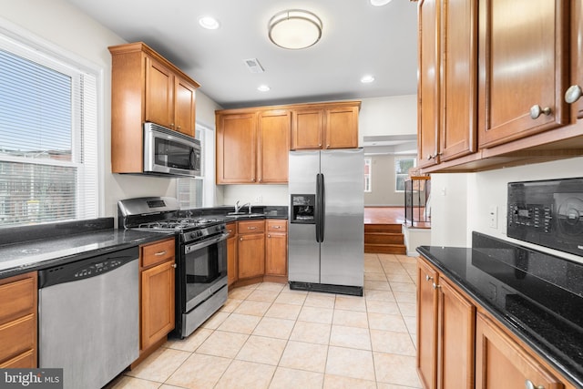 kitchen with stainless steel appliances, brown cabinets, visible vents, and light tile patterned floors