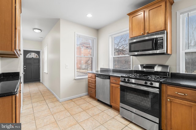 kitchen featuring brown cabinets, light tile patterned floors, stainless steel appliances, recessed lighting, and baseboards