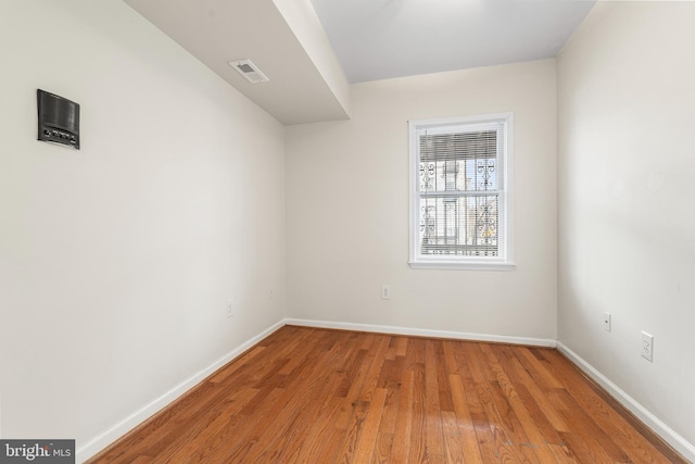 empty room with baseboards, visible vents, and wood finished floors