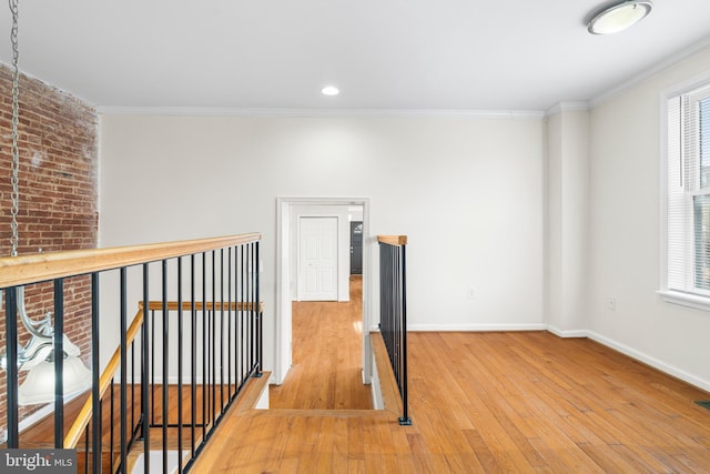 hall with an upstairs landing, baseboards, crown molding, and hardwood / wood-style floors