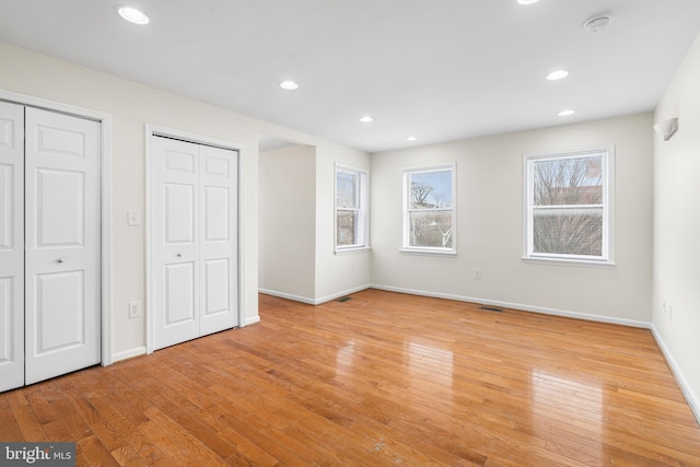 unfurnished bedroom featuring light wood-style floors, two closets, and recessed lighting