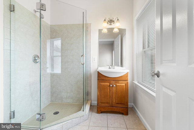 full bathroom with a stall shower, tile patterned flooring, baseboards, and vanity