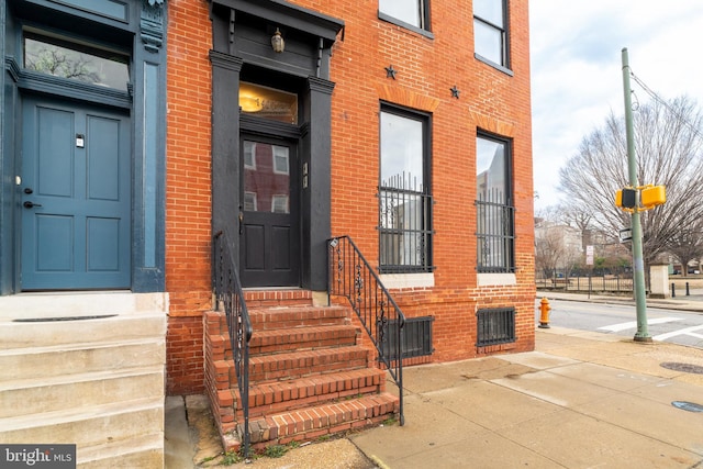 view of exterior entry featuring brick siding