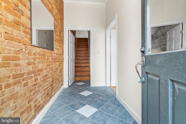 corridor featuring baseboards, brick wall, stairway, and crown molding