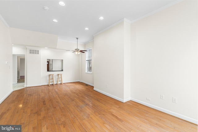 unfurnished living room featuring ceiling fan, visible vents, baseboards, light wood-type flooring, and crown molding