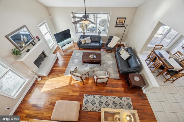 living room featuring ceiling fan, light hardwood / wood-style floors, and a brick fireplace