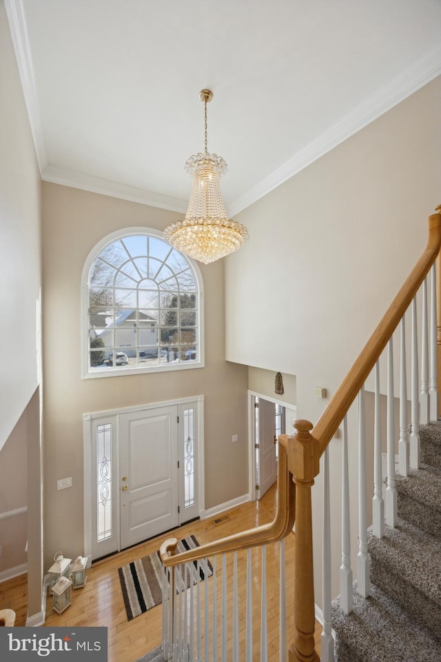 entrance foyer featuring crown molding, hardwood / wood-style flooring, a chandelier, and a high ceiling