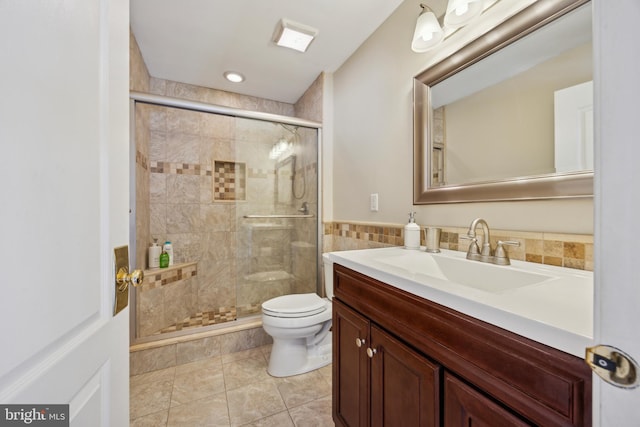 bathroom featuring a shower with door, tile walls, vanity, tile patterned floors, and toilet