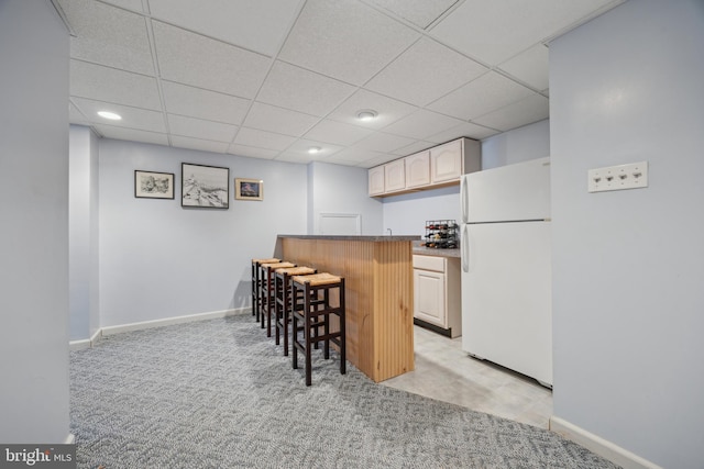 kitchen with white refrigerator, light carpet, a kitchen bar, and kitchen peninsula