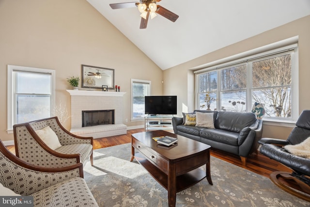 living room featuring ceiling fan, high vaulted ceiling, hardwood / wood-style floors, and a brick fireplace