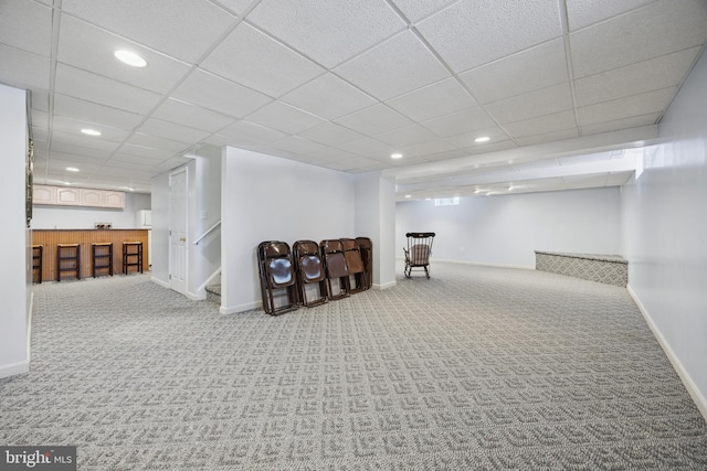 basement with a paneled ceiling and carpet