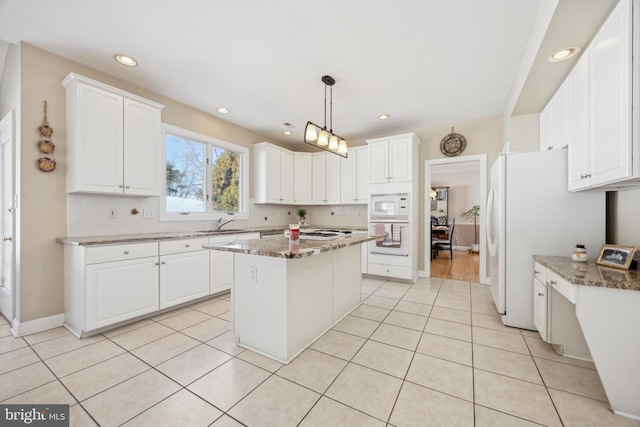 kitchen featuring hanging light fixtures, a kitchen island, stone countertops, and white cabinets