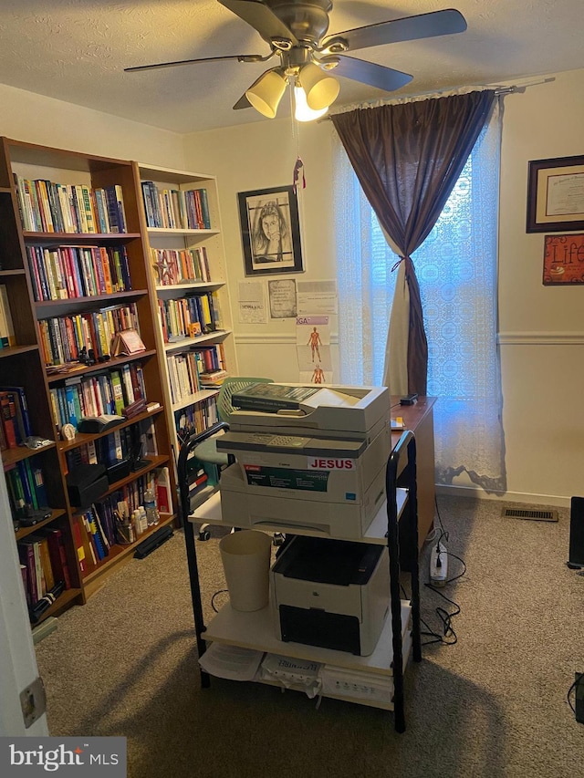 home office featuring ceiling fan, carpet, and a textured ceiling