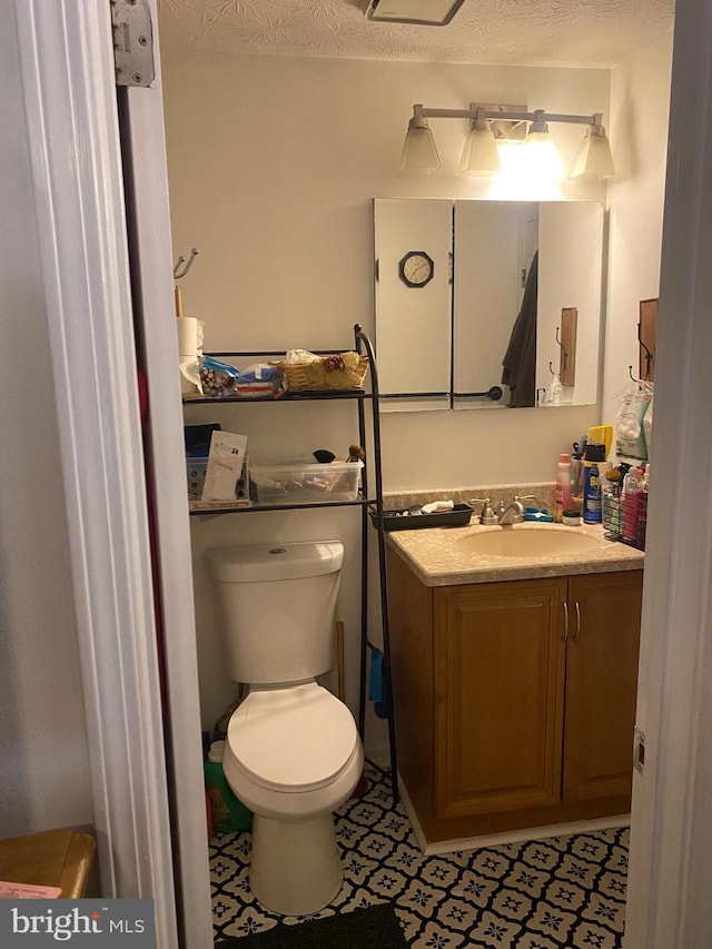 bathroom featuring tile patterned flooring, vanity, a textured ceiling, and toilet