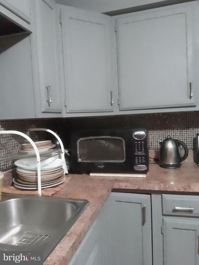 details featuring tasteful backsplash, white cabinetry, and sink