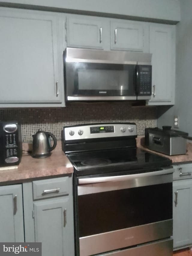 kitchen featuring decorative backsplash, stainless steel appliances, and white cabinets