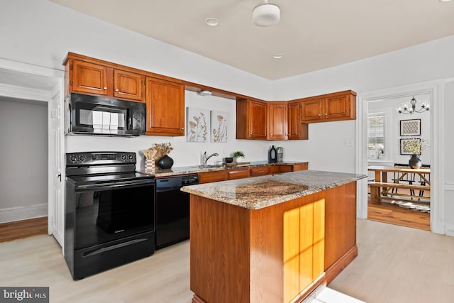 kitchen with stone counters, a kitchen island, light wood-type flooring, and black appliances