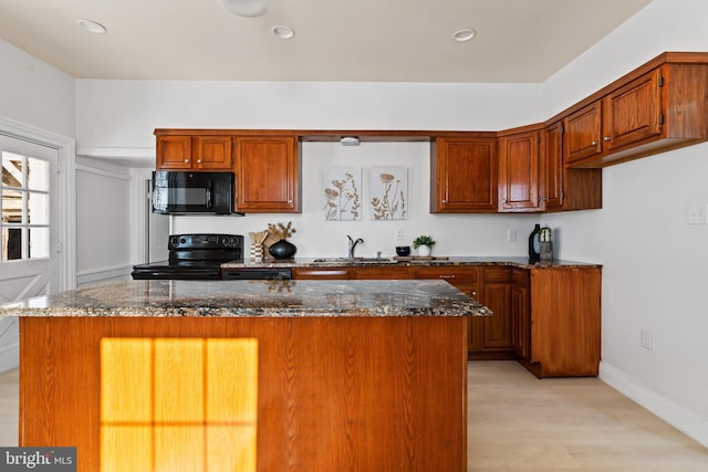 kitchen with sink, black appliances, dark stone counters, and light wood-type flooring