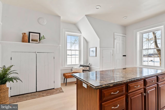 kitchen with light hardwood / wood-style flooring, a wealth of natural light, and dark stone countertops