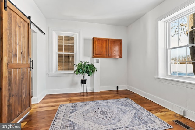 interior space with cabinets, hookup for a washing machine, light hardwood / wood-style floors, and a barn door