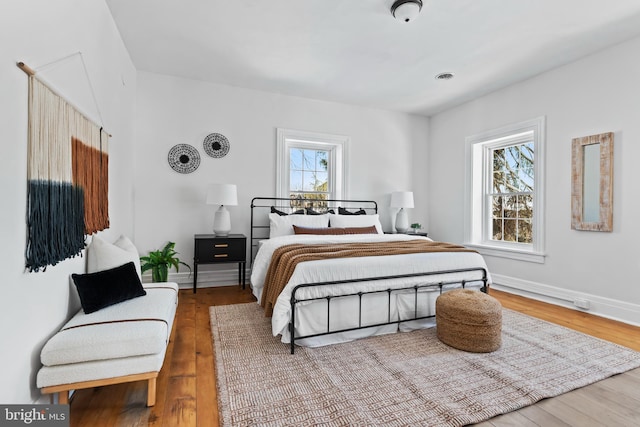 bedroom with hardwood / wood-style flooring and multiple windows