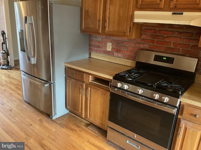 kitchen featuring stainless steel appliances, exhaust hood, and light wood-type flooring