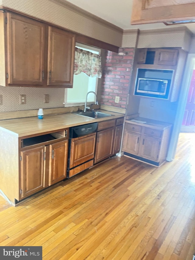 kitchen with ornamental molding, sink, and light wood-type flooring