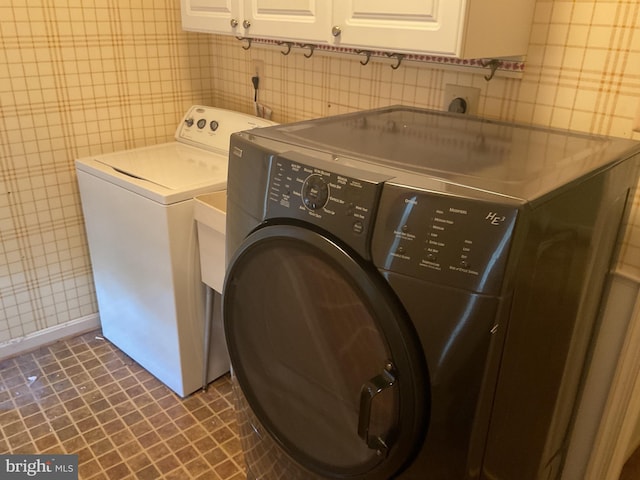 clothes washing area featuring washing machine and dryer and cabinets