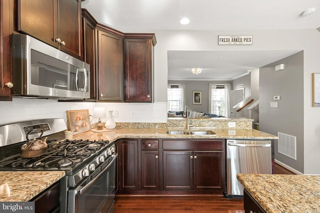 kitchen featuring sink, backsplash, kitchen peninsula, and appliances with stainless steel finishes