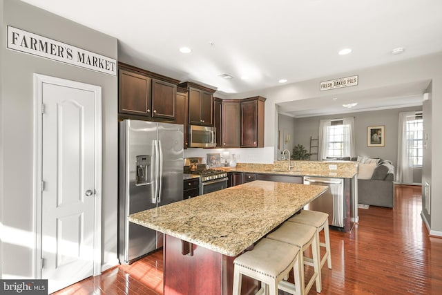 kitchen featuring a kitchen island, sink, a kitchen bar, kitchen peninsula, and stainless steel appliances