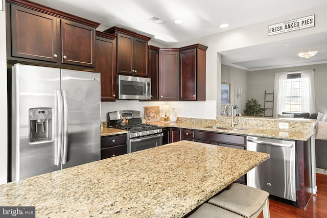 kitchen with a breakfast bar, sink, light stone counters, dark hardwood / wood-style flooring, and stainless steel appliances