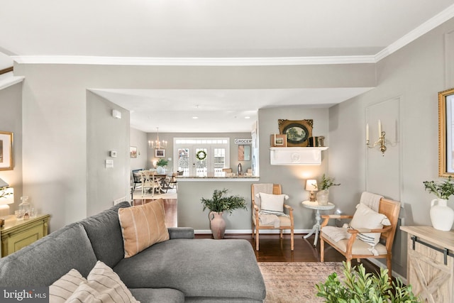 living room featuring hardwood / wood-style flooring, ornamental molding, and a notable chandelier