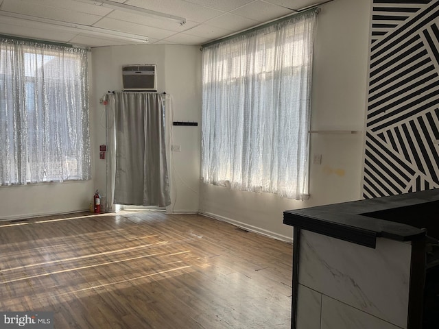 spare room featuring hardwood / wood-style flooring, a paneled ceiling, and a wall mounted AC