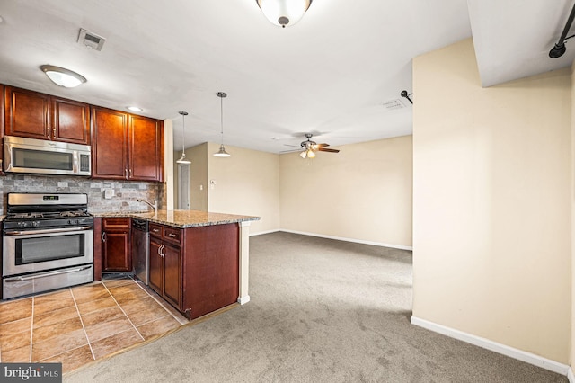 kitchen with appliances with stainless steel finishes, kitchen peninsula, light carpet, and hanging light fixtures