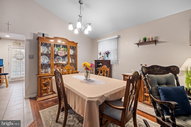 dining room featuring a notable chandelier, a wealth of natural light, vaulted ceiling, and wood-type flooring