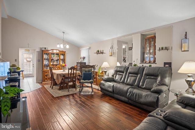 living room featuring lofted ceiling, dark hardwood / wood-style floors, and a chandelier