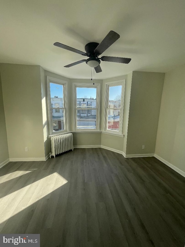 spare room featuring ceiling fan, radiator, and dark hardwood / wood-style flooring